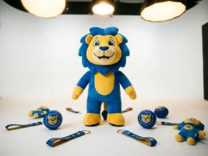 Branded mascot costume displayed with promotional keychains, stress balls, and plush toys on white surface in cobalt blue and golden yellow.