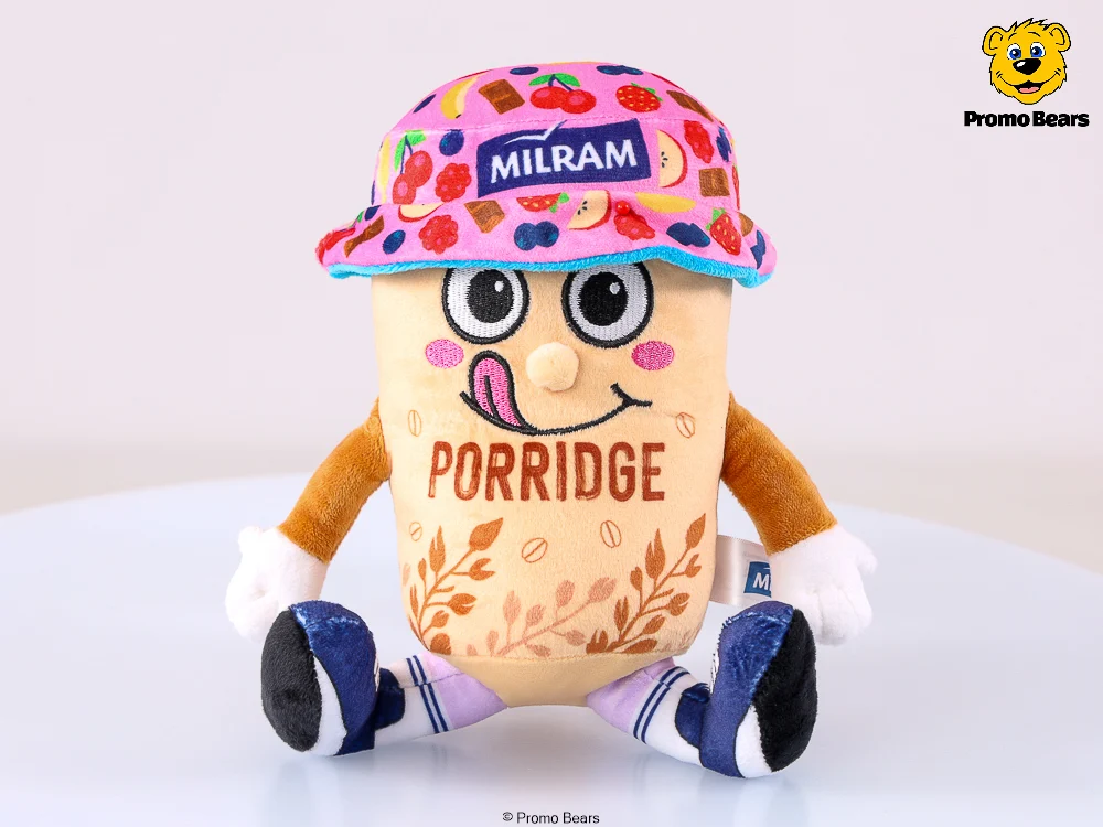 MILRAM Porridge Plüschtiere als Werbeartikel — individuelles Kuscheltier von Promo Bears, sitzende Porridge-Becher-Figur mit Früchte-Bucket-Hat